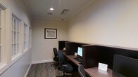 This single-floor business center offers a practical and well-appointed workspace designed to meet the needs of professionals and travelers alike. The room features a clean, neutral color palette with cream-toned walls accented by classic crown molding, lending the space a polished and professional appearance. Recessed lighting provides consistent illumination throughout, complemented by a well-maintained ceiling with integrated ventilation.

The workstation area is equipped with multiple dedicated computer terminals, each set within dark wood-paneled desk dividers that provide a degree of privacy between users. Ergonomic task chairs accompany each station, ensuring comfort during extended use. Desktop computers with full keyboards are readily available, making the space well-suited for tasks such as printing, emailing, or general productivity work.

A framed map print adorns the wall, adding a subtle decorative touch without distracting from the room's functional purpose. The patterned carpeted flooring adds warmth and helps define the space as a quiet, focused environment. Overall, this business center strikes a balance between utility and comfort, providing a reliable and professional setting for anyone needing access to computing resources.