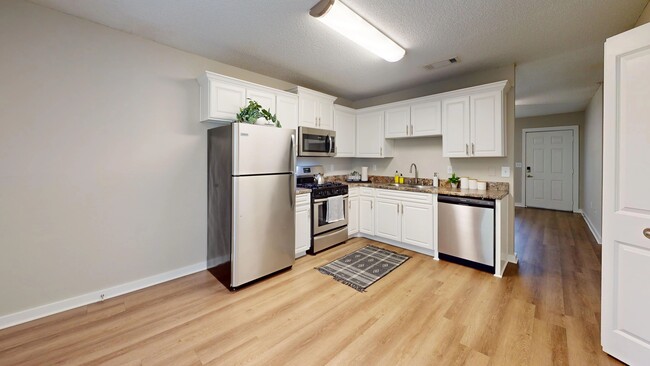 Experience the charm of a huge kitchen and dining area adorned with abundant white cabinetry and granite-inspired countertops for a delightful cooking and dining journey. - Lanier Landing