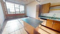This 770 square foot loft-style apartment in Minneapolis offers a harmonious blend of modern design and industrial charm. The space is defined by its expansive floor-to-ceiling windows, which flood the interior with natural light and provide stunning city views. The open floor plan maximizes the sense of space, featuring hardwood flooring throughout.

The kitchen is a standout feature, boasting sleek wooden cabinetry, stainless steel appliances, and striking blue countertops. A central island provides additional workspace and casual dining options. The bathroom continues the contemporary aesthetic with a large vanity, modern fixtures, and a combination tub-shower.

Industrial elements such as exposed ductwork and concrete ceilings add character to the space. Track lighting offers versatile illumination options. The apartment's layout efficiently incorporates living, dining, and sleeping areas, making excellent use of the available square footage.

Storage is well-considered, with built-in closets and kitchen cabinetry. The apartment's location at 740 N Washington Ave places residents in the heart of Minneapolis, offering urban convenience coupled with a stylish, modern living space.