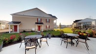 Located at 4170 Green Clover Dr in Hilliard, Ohio, this single-floor property offers a well-designed exterior that combines classic charm with modern community living. The building's façade showcases a combination of neutral vinyl siding and stone base accents, complemented by bold red shutters and a striking red front door that add character and curb appeal. A covered entryway provides a welcoming sense of arrival.

The outdoor living space is a notable highlight of this property. A generously sized concrete patio extends from the building and is furnished with ornate wrought-iron dining sets, making it an ideal setting for outdoor gatherings and relaxation. The surrounding landscaping features neatly maintained greenery, flowering plants, and open lawn areas that enhance the sense of space and tranquility.

Views from the patio extend across a lush, open green space, offering serene sightlines toward neighboring buildings and a community pond in the distance. The setting reflects a well-maintained residential community atmosphere. The property benefits from its location in Hilliard, a vibrant suburb of Columbus, Ohio, known for its strong community character, accessible amenities, and quality neighborhoods. Overall, this property presents a welcoming and functional space with appealing outdoor features suited for comfortable everyday living.