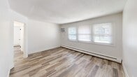 Located at 3712 SE 14th St in Des Moines, Iowa, this 2-bedroom, 1-bathroom unit offers a practical and well-maintained single-floor layout. Throughout the space, wood-look luxury vinyl plank flooring lends a warm, cohesive aesthetic, complemented by crisp white walls and clean white baseboards. The combined kitchen and living area provides an efficient use of space, with the kitchen featuring white shaker-style cabinetry, a white subway tile backsplash, marble-look countertops, a double-basin stainless steel sink, and black appliances including a refrigerator and range. A textured ceiling adds character to the living area, which also benefits from multiple windows that invite natural light. Both bedrooms are comfortably sized with natural light from windows fitted with blinds and baseboard heating units. The primary bedroom includes a built-in sliding-door closet, while the second bedroom offers a window with outdoor views. The bathroom is a standout feature, showcasing a tub-shower combination surrounded by large-format marble-look white tiles and stylish matte black fixtures. A hallway connects the main rooms, completing the functional flow of this tidy, move-in-ready home.