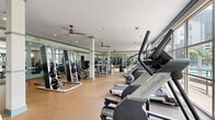 Located at 1055 Pine St in Nashville, TN, this well-appointed fitness center offers a generously sized, single-floor layout designed to accommodate a wide range of workout styles. The space is divided into distinct functional zones, each thoughtfully equipped for specific training needs.

The main floor features durable rubber flooring throughout the strength and cardio areas, while a separate section with hardwood-style flooring is dedicated to functional and group fitness activities. This area includes a freestanding heavy bag, medicine balls, resistance bands, and ample open space for stretching or dynamic movements.

The cardio zone is lined with an impressive selection of machines, including treadmills, ellipticals, StairMaster steppers, and NordicTrack equipment, all positioned to take advantage of the large floor-to-ceiling windows that fill the space with natural light and offer views of the surrounding outdoor area, including a pool courtyard.

The strength training section houses multiple cable machines, weight benches, and a comprehensive dumbbell rack. Floor-to-ceiling mirrors are strategically placed throughout, enhancing the sense of openness. Structural columns with teal accent trim contribute to the space's clean, modern aesthetic, while ceiling fans and recessed lighting ensure a comfortable environment. The overall ambiance is bright, professional, and well-organized.