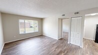 Located at 1000 University Blvd in Kingsport, Tennessee, this 2-bedroom, 1-bathroom unit offers a practical and comfortable single-floor layout. Wood-look hardwood flooring runs throughout the space, providing a warm, cohesive aesthetic from room to room.

The living area is bright and open, featuring a large picture window that invites generous natural light and provides views of the surrounding greenery. A louvered bi-fold closet door and clean neutral walls contribute to a tidy, functional atmosphere. The front entry opens directly into this common area, which connects seamlessly to the rest of the unit.

The kitchen is laid out in a galley style, featuring white cabinetry with modern hardware, light stone-patterned countertops, a stainless steel sink, and black appliances including a refrigerator and range. The efficient design maximizes storage and counter space within the compact footprint.

The spacious primary bedroom offers ample room for furnishings and includes dual closets — a louvered bi-fold closet and an additional open closet — providing generous storage. The second bedroom also features a large window with outdoor views and hardwood-style flooring. The bathroom is clean and functional, with a white vanity, lighted mirror, and wood-look flooring. Textured ceilings are present throughout the unit, completing the interior character of this well-maintained Kingsport residence.