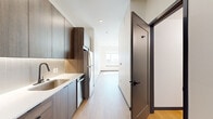 Located at 4228 Kalamath St in Denver's vibrant LoHi neighborhood, this modern studio presents a clean, contemporary design across a single well-organized floor. Light wood-tone flooring runs throughout, lending warmth and visual continuity to the entire space.

The galley-style kitchen is a standout feature, outfitted with rich wood-grain cabinetry extending floor to ceiling for ample storage. Stainless steel appliances — including a refrigerator, electric range, built-in microwave, and dishwasher — complement the crisp white quartz countertops. A subway tile backsplash with under-cabinet lighting adds a refined finishing touch, while a matte black faucet and single-basin sink provide a modern contrast.

The open living area is bright and airy, benefiting from a large window that draws in natural light and frames city views. The space is finished with clean white walls and dark accent baseboards. A dedicated closet with a hanging rod offers practical storage.

The bathroom is appointed with large-format stone-look tile surrounding a full soaking tub and shower, complemented by matte black fixtures including faucet, showerhead, and towel bar. Recessed lighting and light wood flooring maintain the unit's cohesive modern aesthetic throughout.
