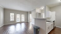 Located at 9955 Buffalo Speedway in Houston, TX, this single-floor home offers four bedrooms, two bathrooms, and three closets within a well-organized layout. The open-concept living room is a standout feature, showcasing rich, dark hardwood-style flooring, crown molding, and a set of French doors that invite natural light and provide outdoor access. The space flows seamlessly into the kitchen, which is separated by a textured breakfast bar. The galley-style kitchen is well-appointed with white shaker cabinets, granite-look countertops, a tile backsplash, and a full suite of stainless steel appliances including a refrigerator, range, microwave, and dishwasher. The bedrooms are finished with plush wall-to-wall carpeting and ceiling fans. The primary bedroom features corner windows that allow for ample natural light, while another bedroom offers the convenience of dual closets with built-in shelving. The bathrooms are clean and functional, featuring granite-look vanity countertops and tiled tub-shower combinations. The primary bathroom includes a soaking tub alongside a separate toilet area. Neutral gray tones throughout the home create a cohesive, modern aesthetic.