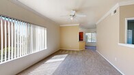 This single-story, 3-bedroom, 2-bathroom home offers a well-designed layout with comfortable living spaces throughout. The open living and dining area greets you at the entry, featuring plush carpet, crown molding, a ceiling fan with light fixture, and wide vertical-blind windows that flood the space with natural light. The adjoining dining nook is accented by a pendant light and flows seamlessly into the kitchen.

The kitchen is well-appointed with warm wood cabinetry, granite-style countertops, a full suite of black appliances including a gas range, built-in microwave, dishwasher, and refrigerator, plus a skylight and a window overlooking the outdoors. Wood-look flooring adds a clean, modern touch.

The primary bedroom offers generous proportions with carpeted flooring, and is complemented by a spacious walk-in closet featuring wire shelving for ample storage. The two additional bedrooms are carpeted and bright, each with panel-style closet doors. Both bathrooms are well-finished; one includes a soaking tub with full tile surround, wood-look flooring, and a vanity with granite-style countertops. A dedicated laundry room houses a full-size washer and dryer with overhead shelving, adding everyday convenience to this practical and inviting home.