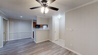 Located at 3003 Windchase Blvd in Houston, TX, this single-story, 2-bedroom, 1-bathroom home offers a functional and comfortable layout with consistent wood-look flooring throughout. The combined living room and kitchen area serves as the heart of the home. The living room is highlighted by a tiled fireplace with a classic white mantle, crown molding, a ceiling fan with integrated lighting, and vertical blinds that allow for natural light control. The galley-style kitchen features warm wood cabinetry, granite-look countertops, a double sink, and white appliances including a range and refrigerator, offering ample storage and prep space. The spacious primary bedroom includes a ceiling fan, a large window with outdoor views, and access to a walk-in closet outfitted with wire shelving for organized storage. The second bedroom also features a ceiling fan, a window with natural light, and mirrored sliding closet doors with gold-tone frames. The bathroom includes wood cabinetry with granite-look countertops and an enclosed tub-shower combination. A hallway connects the bedrooms and bathroom, completing this well-organized, move-in ready layout.