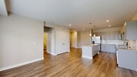 Located at 7505 Founders Way in Franklin, Indiana, this thoughtfully designed one-bedroom, one-bathroom residence offers a comfortable and modern single-floor layout. The open-concept living and kitchen area serves as the heart of the home, featuring warm hardwood-style flooring, recessed lighting, and large windows alongside a glass door that opens to a private balcony, flooding the space with natural light and outdoor views. The kitchen is a standout, boasting grey shaker-style cabinetry, a full suite of stainless steel appliances including a refrigerator with ice maker, range, microwave, and dishwasher, complemented by a granite-topped island with pendant lighting above. A hallway leads from the main living area to the private bedroom, which is finished with plush carpeting, neutral tones, and a window allowing natural light. A dedicated closet provides ample storage. The bathroom features wood-look tile flooring, a combined tub and shower, and a vanity with a stone countertop. The entrance and hallway connect all areas seamlessly, creating a cohesive and functional flow throughout this well-appointed home.