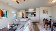 This efficiently designed single-story residence offers a thoughtful layout that maximizes every square foot across its one bedroom and one bathroom. The open-concept main living area seamlessly connects the living room, dining area, and kitchen, creating an inviting and functional space for everyday living. The living room features wood-look flooring, a ceiling fan, and ample natural light, while the dining area provides a dedicated space for meals. The kitchen is equipped with dark espresso cabinetry extending to the ceiling for generous storage, granite-style countertops, and black appliances including a range, microwave, and refrigerator. The bedroom is a comfortable retreat finished with plush carpet, a ceiling fan, natural light from a window, and a closet for storage. The full bathroom mirrors the kitchen's design with dark cabinetry, a granite-topped vanity, and a shower/tub combination. A dedicated in-unit laundry space accommodates a full-size washer and dryer. Neutral warm-toned walls throughout create a cohesive and welcoming ambiance, making this a practical and comfortable place to call home.