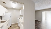 Located at 1110 Garden Walk Blvd in Atlanta, GA, this single-floor residence offers a practical and comfortable layout with 2 bedrooms, 2 bathrooms, a dining room, kitchen, hallway, closet, and dedicated laundry area. The entryway opens into a hallway with rich, dark wood-look flooring that extends throughout the main living areas, creating a cohesive and easy-to-maintain foundation underfoot. The living area flows naturally into the dining space, where a ceiling fan and a sliding glass door with vertical blinds allow natural light to fill the room and provide access to an outdoor view of the surrounding greenery. The kitchen is efficiently designed with white cabinetry, light stone-look countertops, and white appliances including a refrigerator and electric range, all complemented by wood-look tile flooring. Both bedrooms feature plush carpeting, neutral-toned walls, and textured ceilings. The spacious primary bedroom offers ample room for furnishings, while the secondary bedroom includes a window with blinds that invites natural light. The two bathrooms are clean and functional, with one featuring a tub/shower combination, wood-look flooring, and a vanity with a stone-look countertop. A dedicated laundry area with washer and dryer hookups rounds out this thoughtfully organized residence.