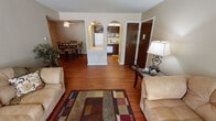 Located at 302 S Rue Flambeau St in South Bend, Indiana, this single-floor residence offers a well-organized layout connecting the main living spaces through a series of distinctive architectural arches. The living area features warm hardwood flooring and neutral-toned walls, creating an inviting atmosphere. A large sliding glass door floods the room with natural light while providing an outdoor view, and ample space accommodates comfortable seating arrangements.

A central arched divider wall serves as a defining architectural element, visually separating the living room from both the kitchen and dining area while maintaining an open, connected feel. The kitchen is accessed through one of two prominent arched openings and is equipped with dark wood cabinetry extending to the ceiling, a stainless steel sink, a dishwasher, and an electric range. A pass-through counter adds functional versatility.

The dining area, positioned off the living room, features a ceiling fan and hardwood flooring, providing a cozy space for meals. The bedroom offers plush carpeting, a window with natural light, and generous space for furnishings. The bathroom includes a tub-shower combination with yellow tile surround, hardwood-style flooring, and a vanity with sink, all illuminated by a ceiling light panel.