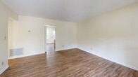 Located at 1655 Central Dr in Southern Pines, NC, this single-floor, 2-bedroom, 1-bathroom home offers a practical and comfortable layout. Wood-look flooring runs consistently throughout the entire space, giving each room a cohesive, clean appearance.

The living room is a welcoming entry point, characterized by a distinctive red front door and a window that lets in natural light, creating a bright and open feel. The space connects seamlessly to the rest of the home through a central hallway.

The kitchen features warm-toned oak cabinetry with ample upper and lower storage, light granite-style countertops, and white appliances including a refrigerator, electric range, and sink. A window above the range adds natural light to the workspace.

The primary bedroom is a generously sized room offering two closets — including a large bifold closet — a window with outdoor views, and textured ceilings. The second bedroom is comparably comfortable, with a window overlooking lush greenery and easy access to the hallway. A third room with built-in closet shelving provides additional flexible space.

The full bathroom includes a clean, white tub-shower combo with built-in shelving and chrome fixtures. Throughout the home, neutral cream-toned walls and textured ceilings provide a calm, understated backdrop suitable for a variety of interior styles.