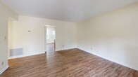 Located at 1655 Central Dr in Southern Pines, NC, this single-floor, 2-bedroom, 1-bathroom home offers a practical and comfortable layout. Wood-look flooring runs consistently throughout the entire space, giving each room a cohesive, clean appearance.

The living room is a welcoming entry point, characterized by a distinctive red front door and a window that lets in natural light, creating a bright and open feel. The space connects seamlessly to the rest of the home through a central hallway.

The kitchen features warm-toned oak cabinetry with ample upper and lower storage, light granite-style countertops, and white appliances including a refrigerator, electric range, and sink. A window above the range adds natural light to the workspace.

The primary bedroom is a generously sized room offering two closets — including a large bifold closet — a window with outdoor views, and textured ceilings. The second bedroom is comparably comfortable, with a window overlooking lush greenery and easy access to the hallway. A third room with built-in closet shelving provides additional flexible space.

The full bathroom includes a clean, white tub-shower combo with built-in shelving and chrome fixtures. Throughout the home, neutral cream-toned walls and textured ceilings provide a calm, understated backdrop suitable for a variety of interior styles.