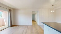 Located on S La Brea Avenue in Los Angeles, this clean and thoughtfully updated 2-bedroom, 1-bathroom single-floor home offers a cohesive modern aesthetic throughout. Light wood-tone flooring flows seamlessly across the living spaces and bedrooms, creating a warm and airy ambiance that complements the crisp white walls found throughout the home.

The kitchen and dining area form an inviting open hub at the heart of the home. The kitchen is equipped with white shaker cabinetry, a sleek gray countertop island, and stainless steel appliances including a full-size French door refrigerator. The adjacent dining space is defined by a stylish gold multi-arm pendant chandelier and large-format light tile flooring, adding a refined touch to the everyday dining experience.

Both bedrooms are bright and well-proportioned, benefiting from natural light through slatted window blinds with views of surrounding greenery. The primary bedroom features a sliding door that opens to a private outdoor balcony area, while a dedicated walk-in closet provides practical storage. The second bedroom includes a sliding closet door for added convenience.

The bathroom is elegantly appointed with a wide gray shaker-style vanity, marble-patterned countertop, dual mirrors, and brushed nickel fixtures, delivering a polished, spa-inspired finish. A connecting hallway ties the layout together efficiently.