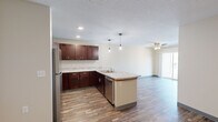 This efficiently designed 2-bedroom, 1-bathroom single-floor residence offers a thoughtful layout with modern finishes throughout. The open-concept kitchen is a standout feature, showcasing rich dark-stained cabinetry, granite-look countertops, a peninsula with a built-in sink, and a full suite of stainless steel appliances including a refrigerator, range, microwave, and dishwasher. Stylish pendant lighting hangs above the peninsula, adding a contemporary touch. Wood-look plank flooring runs consistently throughout the entire space, lending a cohesive and clean aesthetic.

The living room is bright and inviting, featuring a ceiling fan, a sliding glass door that invites natural light and provides outdoor access, and ample wall space for flexible furniture arrangements. Both bedrooms are comfortably sized, each equipped with ceiling fans and natural light from windows. One bedroom includes mirrored sliding closet doors, while a dedicated walk-in closet with a full rod system provides additional storage. The bathroom features wood-look flooring, a glass-enclosed shower, and clean neutral tones. The overall ambiance of the space is modern, neutral, and move-in ready.