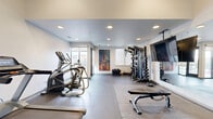 Located at 757 N Grant St in Denver, Colorado, this fitness center offers a thoughtfully designed exercise space across a single floor. The room features a clean, modern aesthetic with white walls, recessed lighting, and durable dark tile and rubber flooring that together create a functional yet polished atmosphere.

The space is well-appointed with a comprehensive selection of equipment to support a wide range of workout routines. Cardio options include a treadmill, elliptical, and stationary bike, while strength training is served by a multi-functional cable machine, adjustable weight bench, and selectorized machines. A full dumbbell rack stocked with hex weights, kettlebells, medicine balls, resistance bands, and barbell plates rounds out the free weights section, offering versatility for users at all fitness levels.

Large floor-to-ceiling glass doors and windows along one wall allow abundant natural light to fill the room and provide views toward the surrounding Denver neighborhood, creating an inviting and energizing environment. A wall-mounted flat-screen TV and a large mirror further enhance the space, making workouts both entertaining and easy to monitor. A vibrant abstract painting adds a touch of artistic character to the interior. The overall layout is open and spacious, allowing for comfortable movement between equipment stations.