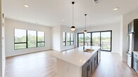 Located at 531 Laketower Drive in Lexington, Kentucky, this modern 2-bedroom, 2-bathroom residence offers a thoughtfully designed open-concept layout with high-end finishes throughout. The combined kitchen and living area serves as the heart of the home, anchored by a generous island with a sleek quartz countertop, undermount sink, and matte black pendant lighting. The kitchen features gray shaker cabinetry, white subway tile backsplash, and stainless steel appliances, all flowing seamlessly into the bright living area. Large black-framed windows and a wide sliding glass door flood the space with natural light and open to a private balcony with sweeping treetop and lake views. Light-toned hardwood flooring runs throughout the main living areas, adding warmth to the contemporary aesthetic. The primary bedroom is generously sized, featuring expansive windows with lake views and direct access to the en-suite bathroom, which includes a dual-sink white vanity with quartz counters, tile flooring, and a frameless glass walk-in shower. The second bedroom offers plush carpet, a large picture window with lake views, and convenient access to the main hall. Three closets, including a walk-in with wire shelving, provide ample storage. Clean white walls, panel-style doors with matte black hardware, and recessed lighting complete the refined, modern character of this well-appointed residence.
