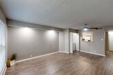 Located at 2408 Houma Blvd in Metairie, Louisiana, this one-bedroom, two-bathroom residence offers a well-organized single-floor layout with a neutral color palette and consistent finishes throughout. The entryway opens into a welcoming living area featuring durable wood-look flooring, textured ceilings, and a ceiling fan with integrated lighting. A large window allows natural light to filter in, creating a bright and open atmosphere. The kitchen is thoughtfully appointed with white cabinetry, granite-style countertops, a subway tile backsplash, stainless steel sink, and white appliances including a range and refrigerator. A pass-through opening connects the kitchen to the living area, enhancing the sense of openness. The bedroom is carpeted for comfort and includes a ceiling fan and a window with blinds providing natural light. Two hallways connect the rooms, with a dedicated closet adding convenient storage. Both bathrooms are finished with granite-top vanities and white cabinetry. The primary bathroom features a large framed mirror, modern light fixture, and a shower-tub combination. The second bathroom is compact and functional. Throughout the space, clean white baseboards and warm-toned walls contribute to a cohesive, move-in-ready aesthetic.