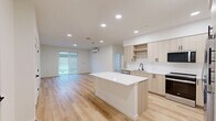 Located at 6021 Lakewood Dr W in University Place, WA, this thoughtfully designed single-story home offers three bedrooms, two bathrooms, and a well-appointed layout across a comfortable footprint. The open-concept living, dining, and kitchen area serves as the heart of the home, featuring light wood-tone cabinetry with matte black hardware, white quartz countertops, a central island, and a full suite of stainless steel appliances including a range, microwave, dishwasher, and refrigerator. Recessed lighting illuminates the space, while sliding glass doors invite natural light and provide outdoor access. Light-toned luxury vinyl plank flooring runs consistently throughout the entire home, creating a clean and cohesive aesthetic. The bedrooms are bright and well-sized, with the spacious primary bedroom offering a wall-mounted mini-split system for personalized climate control and its own sliding glass door. Each bedroom includes closet storage, and the home features a total of five closets. The bathrooms are finished in a modern style, with light wood vanities, white countertops, matte black fixtures, and a tub/shower combination. A dedicated laundry area and additional storage spaces add functional convenience to this move-in-ready home.