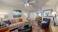 This single-story residence offers a cohesive and functional layout designed for comfortable everyday living. The living room serves as the heart of the home, featuring hardwood-style flooring, a ceiling fan with integrated lighting, and a textured ceiling. Large windows dressed with plaid curtains allow natural light to fill the space, creating a warm and inviting atmosphere that flows directly into the dedicated dining area. The dining room accommodates a full-sized table and provides additional natural light through a window with classic blinds and draping curtains.

The galley-style kitchen is efficiently designed with warm wood cabinetry, light countertops, a double-basin sink, a dishwasher, and a range. A rear door with a window offers added brightness and convenient access.

The primary bedroom features carpeted flooring, multiple windows on adjacent walls, and a ceiling fan, providing a calm and airy retreat. A second, smaller carpeted room offers flexibility as a guest room or office. Both bathrooms include a tub-shower combination, wood-vanity cabinetry, and hardwood-style flooring, with windows providing natural ventilation. The overall ambiance throughout is neutral, bright, and comfortably livable.