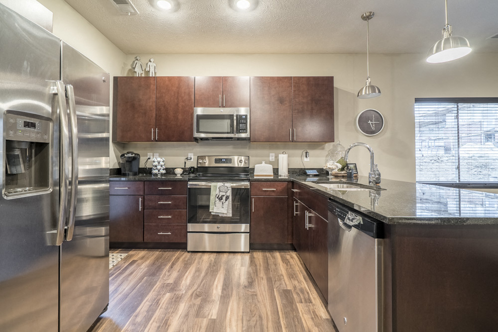 Our traditional design scheme features rich, dark cabinetry with darker granite countertops. - The Villas at Falling Waters