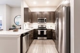 Located at 44 Pennington Rd in New Brunswick, NJ, this single-floor residence offers a thoughtfully designed layout with modern finishes throughout. The entry foyer opens directly toward the kitchen, establishing an immediate sense of the unit's clean, contemporary aesthetic.

The kitchen is a standout feature, equipped with rich dark-brown shaker-style cabinetry extending to the ceiling for ample storage, complemented by bright white countertops and a peninsula with an integrated sink. Stainless steel appliances — including a French door refrigerator with water and ice dispenser, a gas range, and an over-the-range microwave — complete the space. Light-toned hardwood-style flooring flows throughout the main living areas, adding warmth and continuity.

The open living area features a tray ceiling with recessed lighting, neutral walls, and access to a window, creating a bright and airy atmosphere. The bedroom is carpeted for comfort, showcasing a tray ceiling detail, natural light from a large window, and a calm, neutral color palette.

The bathroom is elegantly finished with large-format tile flooring, a dark wood double vanity topped with a white countertop, a well-lit mirror, and a glass-enclosed walk-in shower, delivering a spa-like experience.