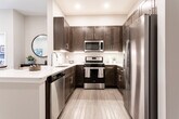 Located at 44 Pennington Rd in New Brunswick, NJ, this single-floor residence offers a thoughtfully designed layout with modern finishes throughout. The entry foyer opens directly toward the kitchen, establishing an immediate sense of the unit's clean, contemporary aesthetic.

The kitchen is a standout feature, equipped with rich dark-brown shaker-style cabinetry extending to the ceiling for ample storage, complemented by bright white countertops and a peninsula with an integrated sink. Stainless steel appliances — including a French door refrigerator with water and ice dispenser, a gas range, and an over-the-range microwave — complete the space. Light-toned hardwood-style flooring flows throughout the main living areas, adding warmth and continuity.

The open living area features a tray ceiling with recessed lighting, neutral walls, and access to a window, creating a bright and airy atmosphere. The bedroom is carpeted for comfort, showcasing a tray ceiling detail, natural light from a large window, and a calm, neutral color palette.

The bathroom is elegantly finished with large-format tile flooring, a dark wood double vanity topped with a white countertop, a well-lit mirror, and a glass-enclosed walk-in shower, delivering a spa-like experience.