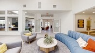 This contemporary 3,020 square foot facility offers a versatile array of spaces designed for work, wellness, and community interaction. The fitness center is a highlight, boasting high ceilings and large windows that flood the space with natural light. It's equipped with state-of-the-art cardio machines, weight training equipment, and ample floor space for various exercise routines.

The facility also includes several office areas, ranging from private rooms to open-concept workspaces. These areas feature modern furnishings, including wooden desks, ergonomic chairs, and sleek storage solutions. Artistic elements, such as abstract wall prints, add visual interest and a touch of sophistication to the work environment.

Communal areas are thoughtfully designed with comfort and collaboration in mind. A lounge space showcases a stylish mix of seating options, including a plush blue sofa and designer armchairs, centered around a unique wooden coffee table. Large glass doors lead to outdoor areas, seamlessly blending interior and exterior spaces.

The overall design aesthetic is clean and minimalist, with a predominantly white color palette accented by warm wood tones and pops of color in the furniture and artwork. Skylights and recessed lighting fixtures contribute to the bright, airy atmosphere throughout the facility. The combination of functionality and style makes this space ideal for a modern, health-conscious community seeking a balance between work and wellness.