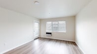 Located at 4719 W Garden Springs Rd in Spokane, WA, this one-bedroom, one-bathroom unit offers a thoughtfully designed, single-floor layout that makes efficient use of its space. The living room is bright and welcoming, featuring light-toned laminate hardwood flooring, neutral walls, and windows with blinds that offer views of the surrounding neighborhood. A wall-mounted HVAC unit and a private exterior door add both comfort and convenience to the living area.

The kitchen is a standout feature, centered around a peninsula with a granite-style countertop, undermount sink, and pendant lighting overhead. Rich, dark wood cabinetry pairs with black appliances — including a range, microwave, and refrigerator — to create a functional and attractive cooking space. The kitchen flows seamlessly into the main living area via durable laminate flooring.

The bedroom is a comfortable, carpeted retreat with a window providing natural light and neighborhood views. The bathroom is clean and practical, featuring wood-tone cabinetry with a granite-style vanity top, a tub/shower combination, a baseboard heater, and laminate flooring. A hallway connects the rooms, completing this well-organized and move-in-ready home.