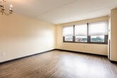 Located at 323 S Broad St in Trenton, NJ, this single-floor unit offers a clean, functional layout with consistent design elements throughout. The main living area is spacious and open, finished with rich hardwood-style flooring and warm neutral walls that create a bright, welcoming atmosphere. A classic chandelier serves as a central lighting fixture, adding a touch of character to the space. Dual windows fitted with horizontal blinds allow ample natural light to filter in while offering views of the surrounding area.

A distinctive pass-through window connects the living area to the kitchen, promoting an open feel between the two spaces. The kitchen is efficiently designed with light wood cabinetry, granite-style countertops, and a white range, providing all the essentials within a compact footprint. An electrical panel is conveniently accessible within the kitchen area.

The hallway leads to a closet with panel doors and connects to the bathroom, which features tile flooring and includes accessibility-friendly grab bars, reflecting a thoughtful and practical design. Throughout the unit, dark baseboards provide a clean contrast against the light walls and flooring, contributing to a polished overall aesthetic. The layout is straightforward and well-organized, making efficient use of the available space.