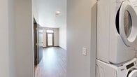 Located at 731 NE Venture Dr in Waukee, Iowa, this efficiently designed studio unit makes smart use of its single-floor layout. Warm wood-look flooring runs continuously throughout the space, providing a cohesive and modern aesthetic.

The kitchen is a standout feature, equipped with a full suite of stainless steel appliances including a refrigerator, range, microwave, and dishwasher. Rich, dark wood cabinetry offers ample storage above and below the counter, while an exposed ductwork detail overhead adds an industrial touch. A wall-mounted TV mount is also included, adding convenience to the living area.

The open living area is bright and clean, with neutral-toned walls, recessed lighting, and a glazed entry door that invites natural light into the space. The layout provides flexibility for a variety of furniture arrangements.

The bathroom features the same wood-look flooring, a walk-in shower, a toilet, and a dark wood vanity with an integrated sink — maintaining the consistent design language found throughout the unit.

A dedicated closet and in-unit laundry hookups, as visible in the 3D overview, round out the practical amenities. This unit offers a well-appointed, functional living environment in the growing Waukee community.