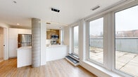 This 680 square foot, one-bedroom apartment in Halifax offers a blend of modern design and functional living. The heart of the home is a sleek, galley-style kitchen featuring white cabinetry, stainless steel appliances, and a contemporary wood accent wall. The kitchen opens to a spacious living and dining area, characterized by light wood flooring and large windows that flood the space with natural light.

The bedroom, spanning 130 square feet, continues the bright and airy theme with a large window offering city views. A sliding barn door adds a touch of rustic charm while maximizing space. The bathroom is pristine and functional, with a full-size tub, modern fixtures, and clean white tiles.

A standout feature is the private terrace, accessible through glass doors, providing an outdoor retreat with expansive views of the Halifax skyline and surrounding area. The apartment also includes an in-unit laundry area with stacked washer and dryer, adding convenience to daily life.

Throughout the space, the design emphasizes clean lines, neutral colors, and an open concept layout, creating a contemporary and inviting atmosphere. Large windows in every room not only provide ample natural light but also offer panoramic views of the city, enhancing the overall living experience in this modern urban dwelling.