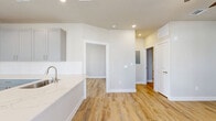 Located in Conroe, TX, this well-appointed one-bedroom, one-bathroom residence offers a thoughtfully designed single-floor layout with a clean, contemporary aesthetic throughout. Light-toned wood-look flooring runs continuously across all rooms, complemented by neutral gray and white walls that create a bright, cohesive atmosphere.

The open kitchen serves as a functional centerpiece, featuring gray shaker-style cabinetry, white quartz countertops with a waterfall-edge peninsula, a stainless steel refrigerator, range, and microwave, as well as recessed lighting overhead. Natural light filters in through multiple windows fitted with horizontal blinds.

The living area provides a comfortable, open feel with a ceiling fan and glass-paned door that leads directly to the private covered patio, which offers open views of the surrounding neighborhood. The bedroom is a well-sized retreat, also equipped with a ceiling fan and a window for natural light.

The bathroom features a gray vanity with a white countertop, a large mirror with overhead lighting, and an adjacent built-in shelving closet for added storage. Three total closets — including a spacious walk-in with multi-tier shelving — provide ample storage solutions. A dedicated laundry area completes this efficient and modern residence.