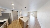 This 1970 square foot home offers a harmonious blend of comfort and functionality across two floors. The ground floor, spanning 1060 square feet, houses the main living areas. The kitchen is a standout feature, boasting light-toned cabinetry, stainless steel appliances, and a convenient island with a double sink. Adjacent to the kitchen, a sliding barn door adds a touch of rustic charm.

The living areas are characterized by their bright, airy ambiance, enhanced by large windows that flood the spaces with natural light. Elegant ceiling fans with integrated lighting fixtures provide both illumination and air circulation. The flooring alternates between warm wood-look planks in the main areas and plush carpeting in the bedrooms, creating a cozy atmosphere.

Upstairs, the 910 square foot space includes two bedrooms, with the primary bedroom measuring a generous 140 square feet. The bathroom features a modern design with a spacious vanity and a shower-tub combination. The home's laundry facilities include full-sized washer and dryer units, complemented by ample storage shelving.

An unexpected highlight is the balcony, offering views of the surrounding area and ongoing construction, hinting at a developing neighborhood. The property's total of two closets ensures adequate storage space. With its thoughtful layout and contemporary finishes, this home presents a perfect balance of style and practicality.