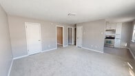 Located at 5867 Poplar Hall Dr in Norfolk, VA, this single-floor unit offers three bedrooms, one bathroom, and four closets within a thoughtfully arranged floor plan. The neutral gray paint palette and clean white trim create a consistent, modern aesthetic throughout.

The spacious primary bedroom is notably generous, offering ample room for furnishings and direct access to multiple closets. The additional bedrooms are carpeted and feature ceiling fans, baseboard heating, and windows that bring in natural light. The layout, as seen in the dollhouse view, positions the bedrooms efficiently around a central corridor.

The kitchen stands out with crisp white shaker-style cabinetry, granite-look countertops, a white subway tile backsplash, and a full suite of stainless steel appliances including a refrigerator and electric range. Light tile flooring and a window overlooking the exterior keep the space bright and functional.

The bathroom features a tub/shower combination with floor-to-ceiling large-format gray tile surround and brushed nickel fixtures, offering a clean and contemporary finish. Baseboard heating units are present throughout the living areas, and a wall-mounted AC unit provides additional climate control. The overall ambiance is clean, move-in ready, and practically designed.