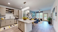 This well-appointed single-floor residence offers a thoughtfully designed open-concept layout that seamlessly connects the kitchen, dining, and living areas. The kitchen is a standout feature, equipped with stainless steel appliances including a French door refrigerator, range, microwave, and dishwasher. Light wood-grain cabinetry, granite countertops, a subway tile backsplash, and a central island with bar seating provide both function and style. Wide-plank hardwood-style flooring flows throughout the main living areas, complementing the bright, neutral color palette.

The living room is highlighted by a striking blue accent wall, large windows that invite abundant natural light, and direct access to an exterior door. Two well-sized bedrooms offer plush carpeting and generous natural light, each with ample space for a full bedroom suite. The bathrooms are finished with granite-topped vanities, wood-grain cabinetry, and tiled tub-shower combinations.

The entry foyer provides a welcoming transition into the home, complete with closet storage. Throughout the residence, recessed lighting, ceiling fans, and a cohesive blue and yellow design palette contribute to a contemporary and inviting ambiance.