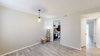 This two-story, 2-bedroom, 2-bathroom residence in Brunswick, Georgia, is thoughtfully laid out across two floors, offering a functional and comfortable living experience. The main floor features two living areas, a dedicated kitchen, and hallways that connect the spaces seamlessly. The galley-style kitchen is appointed with white shaker cabinets with matte black hardware, granite-style countertops, a subway tile backsplash, stainless steel appliances, and hardwood-style luxury vinyl plank flooring. One living area features vertical shiplap-style wall paneling and a pendant light fixture, while the other boasts large sliding glass doors that flood the room with natural light and provide outdoor views. Both bathrooms are finished with granite countertops, white cabinetry, and tiled shower surrounds. The upper floor houses both bedrooms, each with plush carpet flooring and closet space. The spacious primary bedroom features dual closets and a window with natural light. The secondary bedroom also includes a closet and window. Neutral tones throughout create a clean, cohesive aesthetic, making this a well-appointed two-story home in Brunswick, GA.