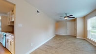 This single-floor residence offers a comfortable and functional layout across two bedrooms and two bathrooms. Wood-look flooring runs consistently throughout the entire unit, providing a cohesive and clean aesthetic in every room. Ceiling fans are installed in the main living areas and both bedrooms, contributing to both comfort and air circulation.

The living area is generously sized, featuring neutral-toned walls, white baseboards, and a front entry door. Natural light enters through windows fitted with horizontal blinds. The space flows naturally toward the galley-style kitchen, which is outfitted with white cabinetry, granite-style countertops, a warm mosaic tile backsplash, stainless steel appliances including a refrigerator, range, and microwave, and track lighting overhead.

Both bedrooms are well-proportioned and receive natural light through large windows. One bedroom features dual closets, offering ample storage. Each bedroom is served by its own full bathroom, both of which include white vanity cabinetry with granite-style countertops, wood-look tile flooring, and a tiled walk-in shower. The overall palette of warm beige tones and white trim creates a clean, neutral ambiance throughout the unit.