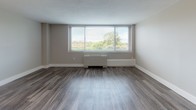 Located at 2000 Riverside Dr in Richmond, Virginia, this single-floor residence showcases a thoughtfully updated interior with consistent wood-look flooring throughout. The open living area is bathed in natural light through large, wide windows fitted with blinds, offering pleasant views of surrounding greenery. A baseboard heating unit runs beneath the windows, complementing the clean, neutral wall tones that create a calm and welcoming atmosphere.

The kitchen is a standout feature, outfitted with white shaker-style cabinetry, granite-look countertops, a subway tile backsplash, and stainless steel appliances including a refrigerator, gas range, and microwave. Track lighting overhead and a peninsula counter add both function and style to this well-designed culinary space.

The bedroom continues the bright, airy aesthetic with its own large window framing outdoor tree views, durable flooring, and ample wall space. The bathroom is cleanly finished with white cabinetry, a solid-surface vanity top, chrome fixtures, and a glass-door shower enclosure, all set on wood-look flooring that ties the space together cohesively. Every room reflects a modern, refreshed design sensibility suited for comfortable everyday living.
