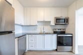 Located at 1200 Talwood Dr in Peterborough, Ontario, this well-appointed one-bedroom, one-bathroom unit offers a clean, modern aesthetic throughout its efficiently designed layout. Light-toned hardwood-style flooring runs continuously across all rooms, lending a cohesive and airy feel to the entire space.

The living room is the standout area of the unit, featuring a large floor-to-ceiling sliding window that draws in abundant natural light and provides open outdoor views, creating a bright and inviting atmosphere. Baseboard heating runs along the perimeter, and crisp white walls complement the light flooring throughout.

The kitchen is thoughtfully designed with white cabinetry, classic white subway tile backsplash, and stainless steel appliances including a range and microwave. It opens conveniently toward the living area, allowing for a functional and connected flow between spaces.

The bedroom is a comfortable, well-sized room featuring a closet and the same warm flooring found throughout. Its clean white walls and simple layout make it a versatile and restful retreat.

The bathroom is finished with full white subway tile surrounding the soaker tub and shower combination, paired with chrome fixtures for a polished, timeless look.

A hallway connects all areas of the unit seamlessly. The overall ambiance is clean, bright, and move-in ready, reflecting a modern and practical residential design.