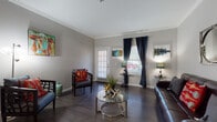 This single-story 1-bedroom, 1-bathroom residence offers a thoughtfully designed layout that balances comfort and functionality. The living area features dark hardwood-style flooring, crown molding, and neutral gray walls that create a clean, contemporary backdrop. Multiple windows dressed with navy drapes and plantation shutters allow natural light to flow throughout, enhancing the open and airy feel of the space. A pass-through opening connects the living area to the kitchen, promoting a seamless open-concept flow.

The kitchen is outfitted with white shaker-style cabinetry, granite-look countertops, a subway tile backsplash, and stainless steel appliances including a range and refrigerator, providing a polished and practical cooking environment.

The bedroom is generously proportioned, featuring plush wall-to-wall carpeting, a tray ceiling with a ceiling fan, and a large window with ample natural light. The room offers a calm, restful ambiance with neutral tones throughout.

The bathroom presents a bright, clean aesthetic with white cabinetry, a wide vanity with a large mirror, and a well-lit fixture bar above. Luxury vinyl plank flooring ties the space together with a modern finish. Overall, this residence offers a cohesive design with quality finishes across every room.