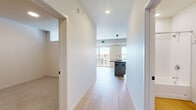 Located at 225 Fourth Ave N in Fargo, North Dakota, this thoughtfully designed two-bedroom, one-bathroom unit offers a contemporary living experience with a clean, modern aesthetic throughout. Light hardwood flooring runs through the main living and kitchen areas, creating a warm and cohesive feel.

The open-concept kitchen serves as the centerpiece of the space, showcasing a large dark-topped island with an integrated sink, gray cabinetry, open shelving, a tile backsplash, and stainless steel appliances including a range with a hood vent and refrigerator. A pendant light fixture adds a stylish focal point overhead. Large windows flood the kitchen with natural light and offer views of the surrounding Fargo cityscape.

A central hallway connects the living areas to the bedrooms and bathroom, maintaining a practical and efficient layout. The primary bedroom features plush carpeting and access to a walk-in closet with built-in wire shelving. The second bedroom is carpeted as well, with a high transom-style window that brings in soft, diffused natural light. The bathroom is clean and functional, equipped with a full tub-shower combination with chrome fixtures and light hardwood-style flooring. The overall ambiance is bright, minimal, and move-in ready.