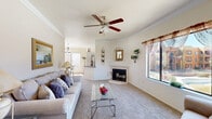 This single-floor residence offers a thoughtfully designed layout across two bedrooms, two bathrooms, an office, and a combined living and dining area. The living room serves as the heart of the home, featuring a ceiling fan, crown molding, a corner fireplace with a tile surround, and a large window that draws in natural light. Soft carpet underfoot and neutral walls create a warm, inviting ambiance throughout.

The dining area is bathed in natural light through a large sliding glass door leading to an outdoor patio, complemented by an additional window and an elegant chandelier overhead. The kitchen is well-equipped with dark granite countertops, light wood cabinetry, hexagonal tile flooring, stainless steel appliances including a gas range, dishwasher, and refrigerator, and a window overlooking the outdoors.

The spacious primary bedroom features large windows with outdoor views and plush carpeting. The second bedroom is comfortably sized with its own closet access. A dedicated office provides a quiet workspace with a window and carpeted flooring. Both bathrooms are finished with hexagonal tile floors and dark granite vanity tops, with one featuring a full tub-shower combination. A hallway and closet complete this functional, well-rounded floor plan.