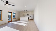 Located at 720 E 36th St in Charlotte, NC, this single-floor, 2-bedroom, 2-bathroom unit offers a clean, modern design with consistent light wood-tone flooring and crisp white walls throughout. The open-concept living and kitchen area anchors the space, flooded with natural light from wood-framed windows. The kitchen is well-appointed with white shaker cabinetry, light quartz countertops, a full suite of stainless steel appliances—including a French door refrigerator, range, built-in microwave, and dishwasher—and a central island with seating overhang. Pendant lighting with warm wood accents hangs above the island, complementing the modern aesthetic. The living area flows naturally from the kitchen, creating a cohesive, functional gathering space. Both bedrooms feature ceiling fans, recessed lighting, natural light from wood-trimmed windows, and light wood flooring. The primary bedroom includes an outdoor view and access to a dedicated walk-in closet with built-in shelving and racking. The bathrooms feature tile flooring, and at least one includes a glass-enclosed walk-in shower with marble-style tile surround and matte black fixtures, adding a refined, contemporary touch throughout.