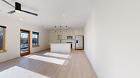 Located at 720 E 36th St in Charlotte, NC, this single-floor, 2-bedroom, 2-bathroom unit offers a clean, modern design with consistent light wood-tone flooring and crisp white walls throughout. The open-concept living and kitchen area anchors the space, flooded with natural light from wood-framed windows. The kitchen is well-appointed with white shaker cabinetry, light quartz countertops, a full suite of stainless steel appliances—including a French door refrigerator, range, built-in microwave, and dishwasher—and a central island with seating overhang. Pendant lighting with warm wood accents hangs above the island, complementing the modern aesthetic. The living area flows naturally from the kitchen, creating a cohesive, functional gathering space. Both bedrooms feature ceiling fans, recessed lighting, natural light from wood-trimmed windows, and light wood flooring. The primary bedroom includes an outdoor view and access to a dedicated walk-in closet with built-in shelving and racking. The bathrooms feature tile flooring, and at least one includes a glass-enclosed walk-in shower with marble-style tile surround and matte black fixtures, adding a refined, contemporary touch throughout.
