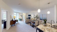 This single-floor residence offers a thoughtfully designed open-concept layout that seamlessly connects the living, dining, and kitchen areas. The living room serves as a central gathering space, highlighted by a tile-surround fireplace, soft carpet flooring, and a wall-mounted television. Natural light filters in through large windows and a sliding glass door that opens to a private balcony, enhancing the bright and airy ambiance throughout.

The kitchen is well-equipped with white raised-panel cabinetry featuring matte black hardware, dark countertops, light hardwood-style flooring, and a full suite of stainless steel appliances including a French door refrigerator, electric range, and over-the-range microwave. A granite-topped peninsula provides additional prep and dining space.

The primary bedroom offers plush carpeting, generous natural light from large windows, and access to a private balcony. Its en-suite bathroom features white cabinetry, a framed mirror, tile flooring, and a shower. The second bedroom is comfortable and well-sized, with a closet and warm, neutral finishes. A second full bathroom with a tub-shower combination and dark vanity cabinetry serves this bedroom. The overall aesthetic is clean, modern, and cohesive throughout.
