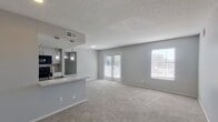 This contemporary apartment showcases a spacious open-concept design, seamlessly blending the living area with a sleek kitchen. The kitchen boasts a marble-top breakfast bar and modern appliances. Multiple bedrooms feature plush carpeting and ceiling fans, while bathrooms are equipped with updated fixtures and marble vanities. Large windows and glass doors flood the space with natural light, complementing the neutral gray walls. The unit includes ample storage with built-in closets. The overall ambiance is one of modern comfort and functionality, perfect for urban living.