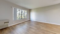 Located in the Valley Village neighborhood of Los Angeles, this 2-bedroom, 3-bathroom single-story home offers a well-designed layout with a clean, modern aesthetic throughout. The open-concept kitchen and living area serve as the heart of the home, featuring light hardwood-style flooring, neutral gray walls, and a ceiling fan overhead. The kitchen is outfitted with white shaker cabinetry, gray countertops, stainless steel appliances including a gas range, built-in microwave, and refrigerator, as well as a skylight that fills the space with natural light. A peninsula with a sink connects the kitchen to the living area, which benefits from a large window overlooking lush greenery. Both bedrooms are carpeted and equipped with ceiling fans, and each offers window views of the surrounding trees, creating a calm, nature-connected atmosphere. The primary bedroom includes access to a dedicated walk-in closet with built-in shelving. Three bathrooms provide convenience and privacy for residents, each featuring tiled flooring and tub-shower combinations with white fixtures and chrome hardware. The overall ambiance is bright, functional, and comfortable, making this a practical and inviting home in the heart of Los Angeles.