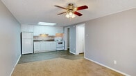 Located at 2100 Apalachee Pkwy in Tallahassee, FL, this single-story, one-bedroom, one-bathroom unit offers a practical and efficiently designed layout across a compact footprint. The interior features a neutral color palette of warm grays and whites throughout, complemented by white trim and textured ceilings.

The kitchen is a standout area, equipped with white cabinetry extending to the ceiling, dark granite-style countertops, a stainless steel sink, and white appliances including a refrigerator and electric range. A recessed skylight panel overhead provides bright, even lighting, and wood-look plank flooring ties the kitchen into the open adjacent living area seamlessly.

The bedroom is a comfortable, carpeted space featuring a ceiling fan with light fixture and a window that allows natural light and outdoor views of surrounding greenery. A full-width bi-fold closet provides ample storage along one wall, while the textured ceiling and crown molding add a finishing detail.

The bathroom includes a white vanity with storage, a wall mirror, wood-look flooring, and a full tub-shower combination. A utility room and hallway complete the layout, contributing to the unit's organized and functional flow throughout.