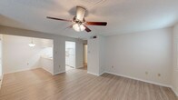 This single-story, one-bedroom, one-bathroom unit features a thoughtfully organized layout that maximizes its comfortable footprint. The open living area is finished with light wood-style hard-surface flooring and neutral gray walls, creating a bright and airy atmosphere. A ceiling fan with integrated lighting serves as a central fixture, enhancing both air circulation and illumination. Multiple windows fitted with horizontal blinds allow natural light to filter through, contributing to the welcoming feel of the space.

The galley-style kitchen is efficiently arranged with white cabinetry lining both walls, offering ample upper and lower storage. Light-toned countertops, tile flooring, a white electric range, dishwasher, and a stainless steel sink complete the kitchen's functional design.

The bedroom is carpeted for added comfort and includes two windows that bring in natural light, along with its own ceiling fan with lighting. The full bathroom features tile flooring, a tub-shower combination with tiled surround, a toilet, and a grab bar for added accessibility. A textured ceiling finish appears throughout the unit, adding a consistent design element across all rooms.